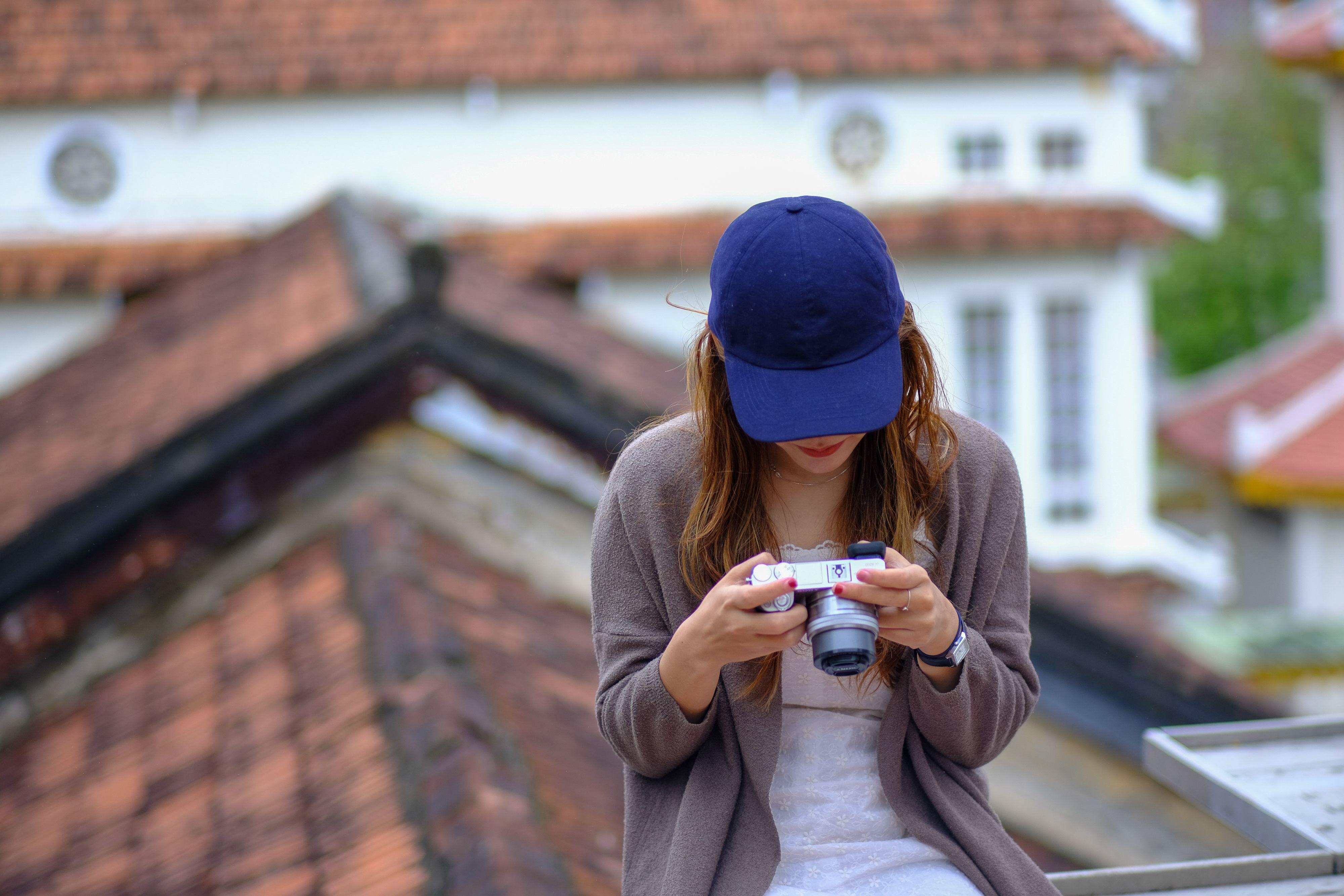 A woman in a cap examines her camera on a Vietnamese rooftop.