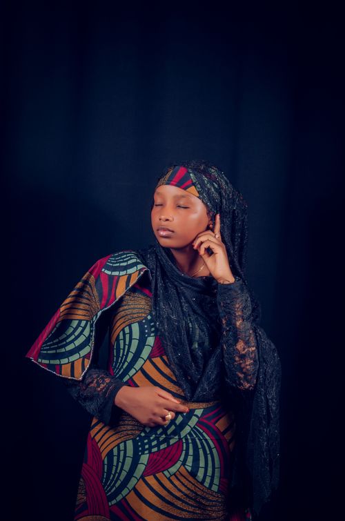 Free Striking portrait of a woman wearing multicolored traditional attire with eyes closed against a dark background. Stock Photo