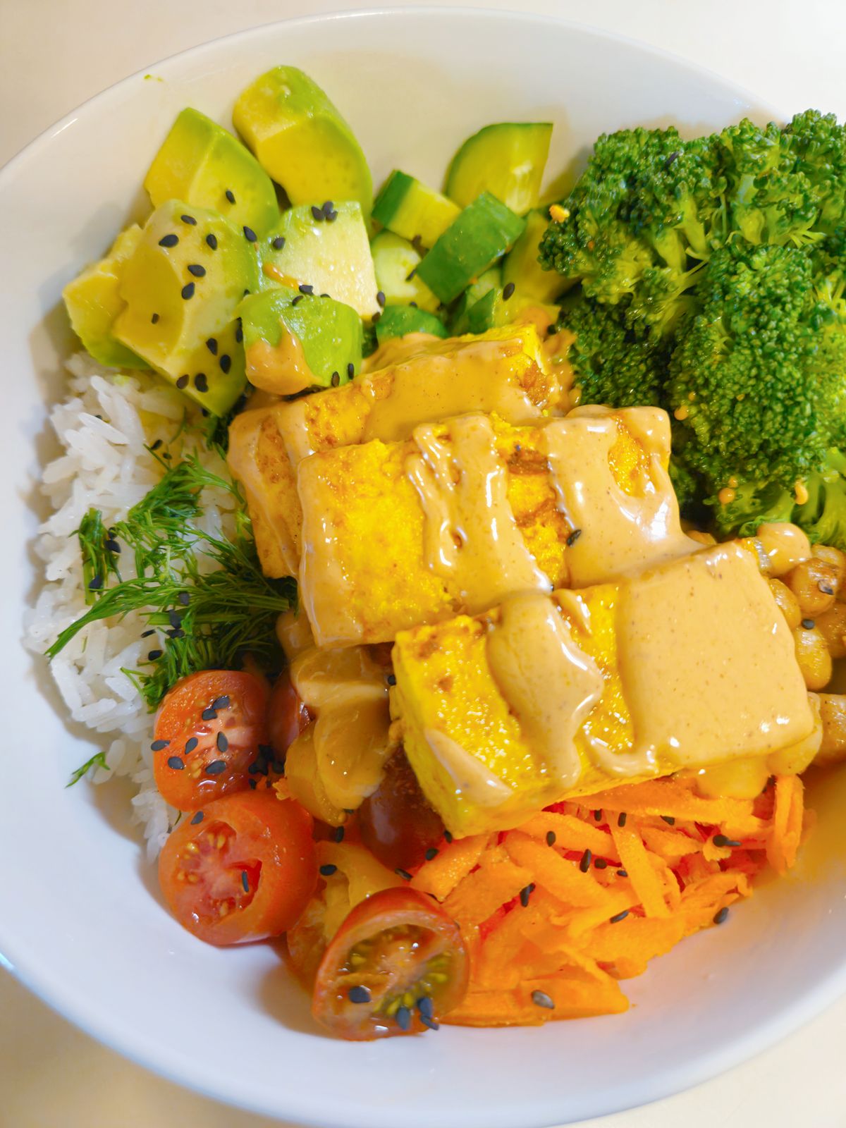 Colorful vegan nourish bowl with tofu, rice, avocado and fresh vegetables
