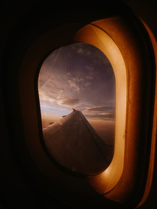 Free A captivating view of a sunset sky through an airplane window, showcasing the horizon and aircraft wing. Stock Photo