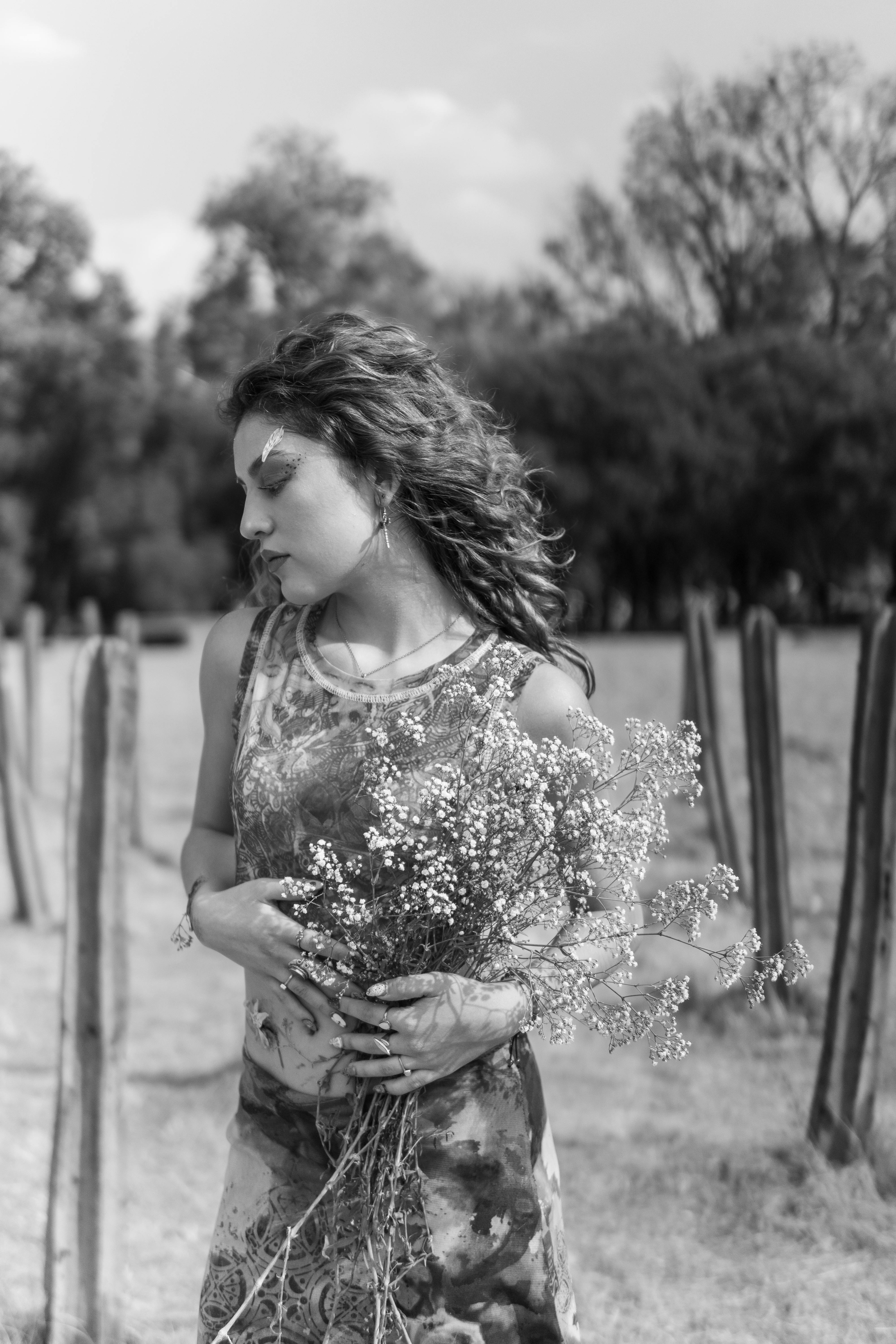 Black and white portrait of a Latina woman with artistic flower makeup in a Mexican field.