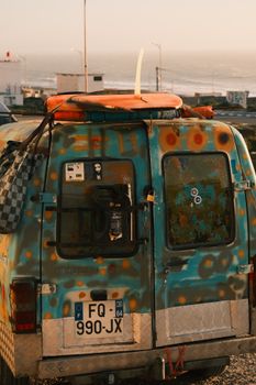 A vintage van with surfboard parked by the ocean at sunset. Perfect for travel and adventure themes.