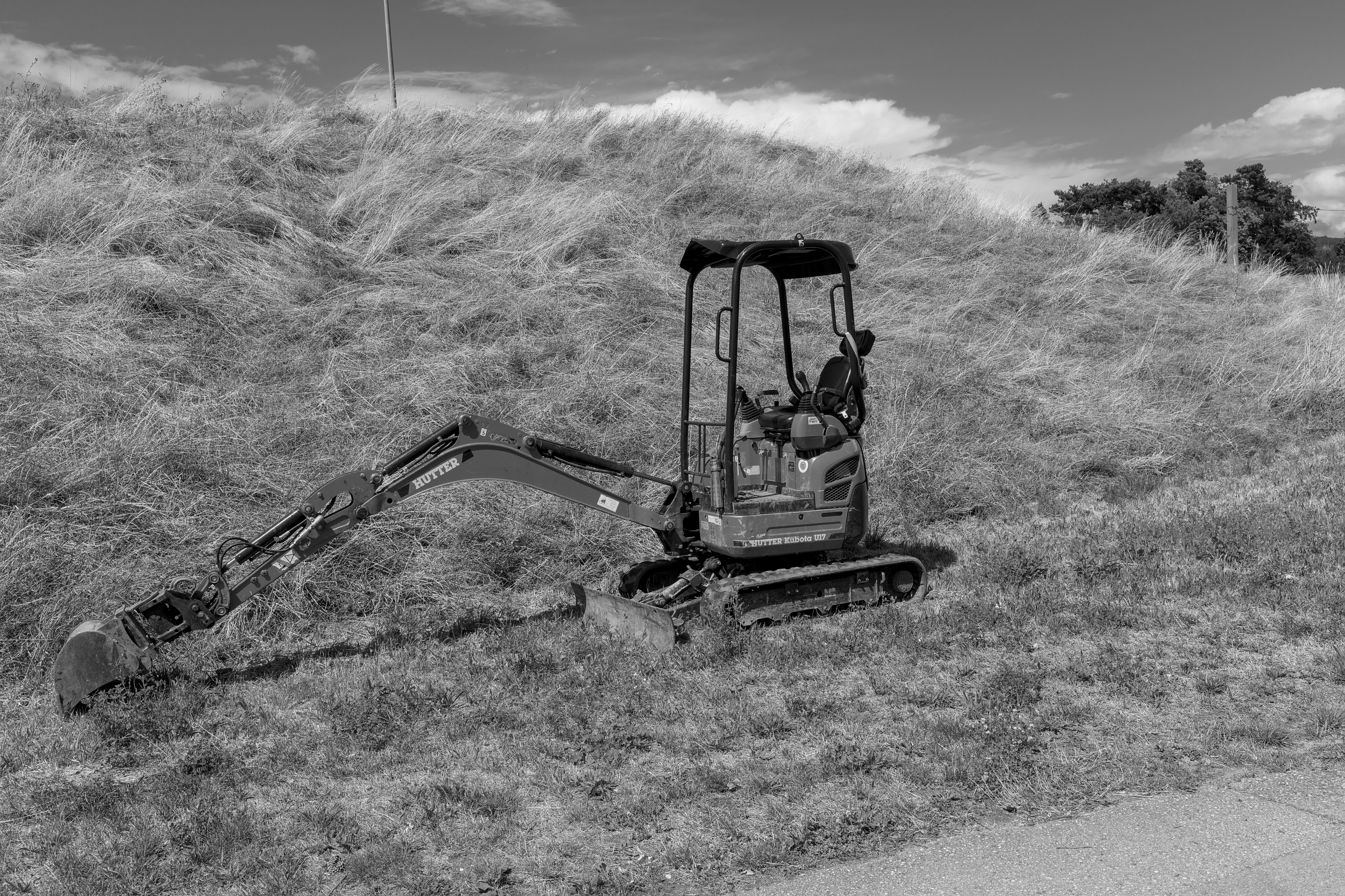Parked mini excavator with worn rubber tracks sitting unused on an Arkansas contractor lot
