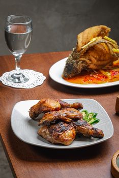 Traditional Indonesian grilled chicken and fish dish served indoors.