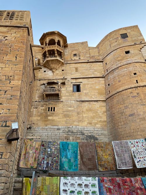 Brightly coloured textiles hung against the sandstone wall of Jaisalmer Fort