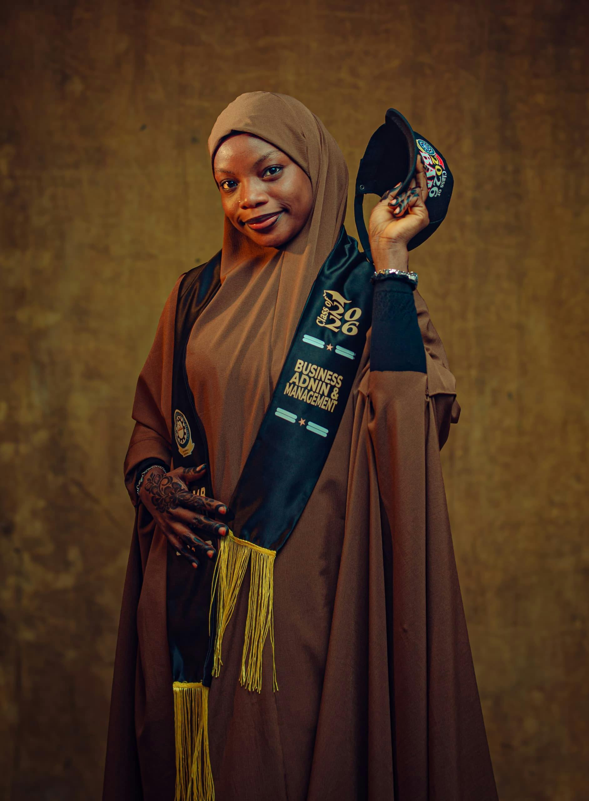 Confident African woman celebrating her business management graduation wearing a hijab and traditional attire.