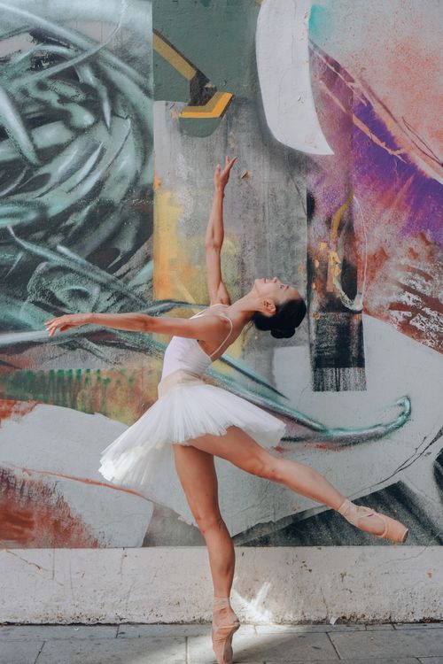Free A graceful ballet dancer performs an elegant pose against vibrant street art in Madrid. Stock Photo