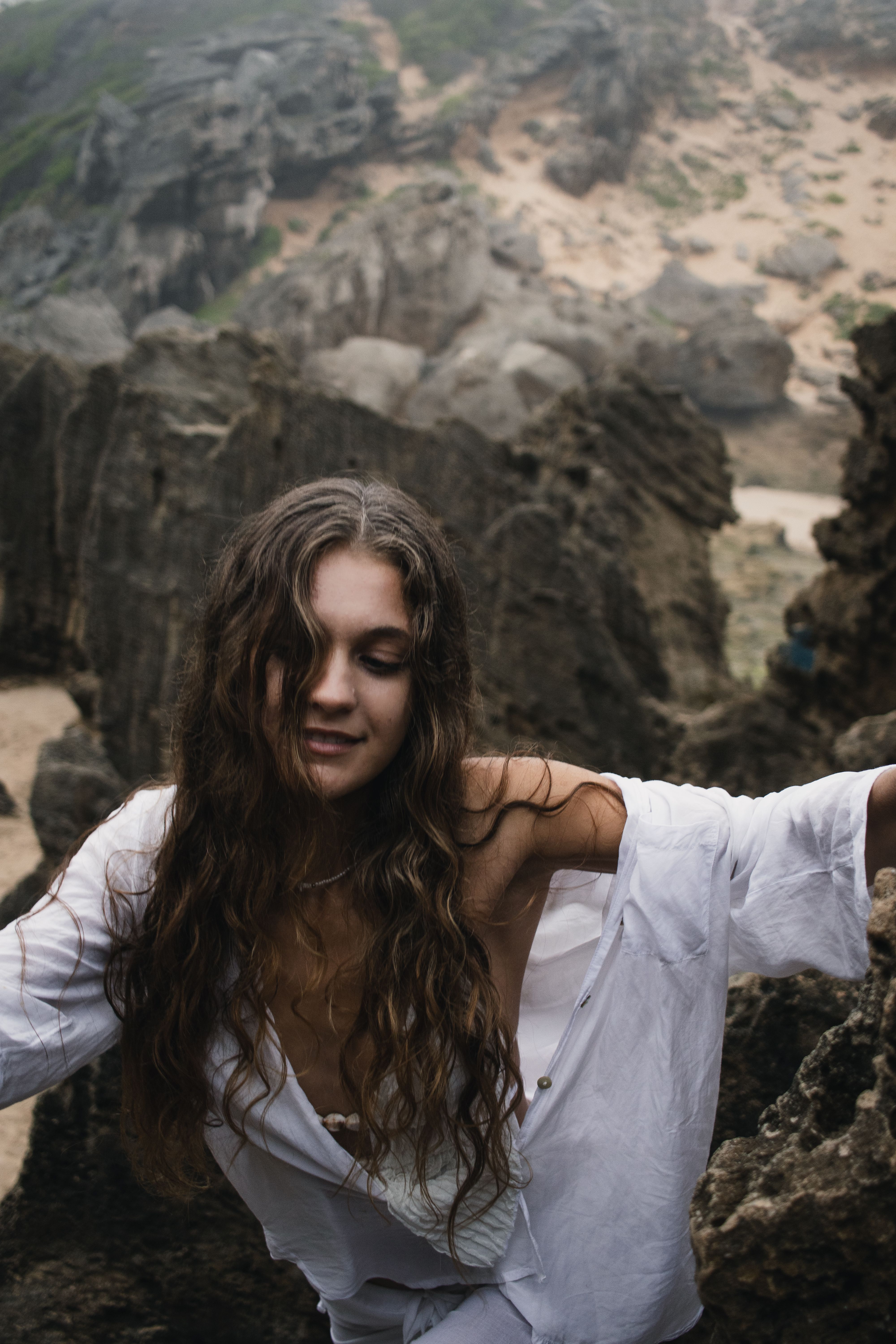 Woman Exploring Rocky Beach in White Shirt · Free Stock Photo