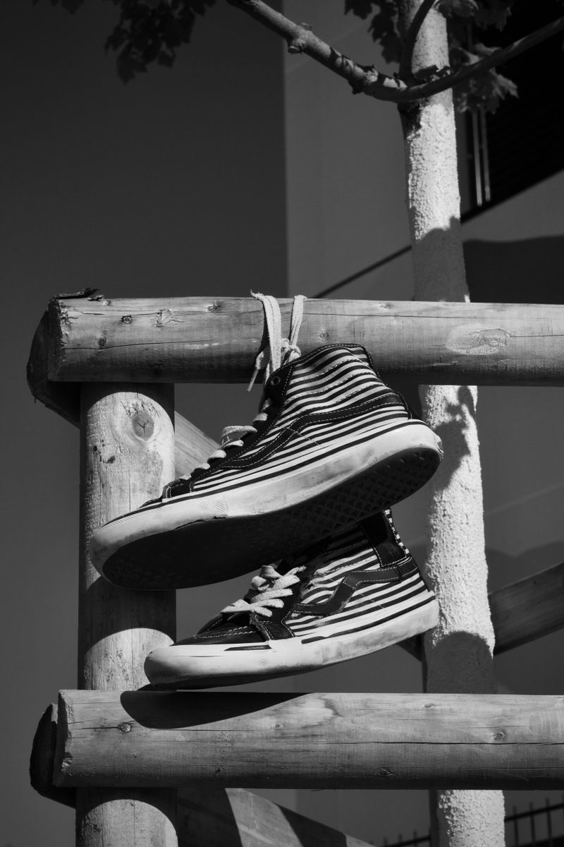 Zapatillas altas de rayas en blanco y negro colgadas de una valla de madera