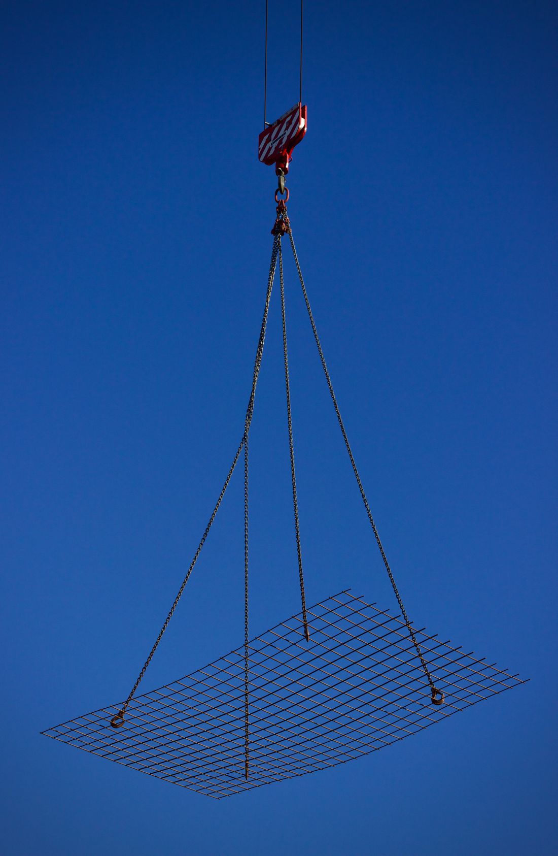 Crane lifting a steel panel against the sky