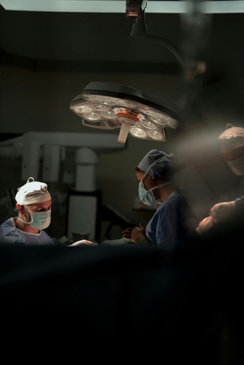 Free Surgeons performing a precise surgical operation under operating room lights. Stock Photo