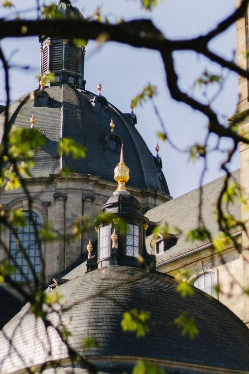 Free A view of a historic church dome framed by lush spring foliage in natural light. Stock Photo