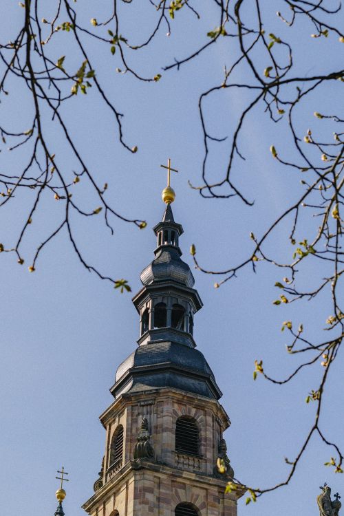 Free A beautiful church tower viewed through budding spring branches against a clear blue sky. Stock Photo