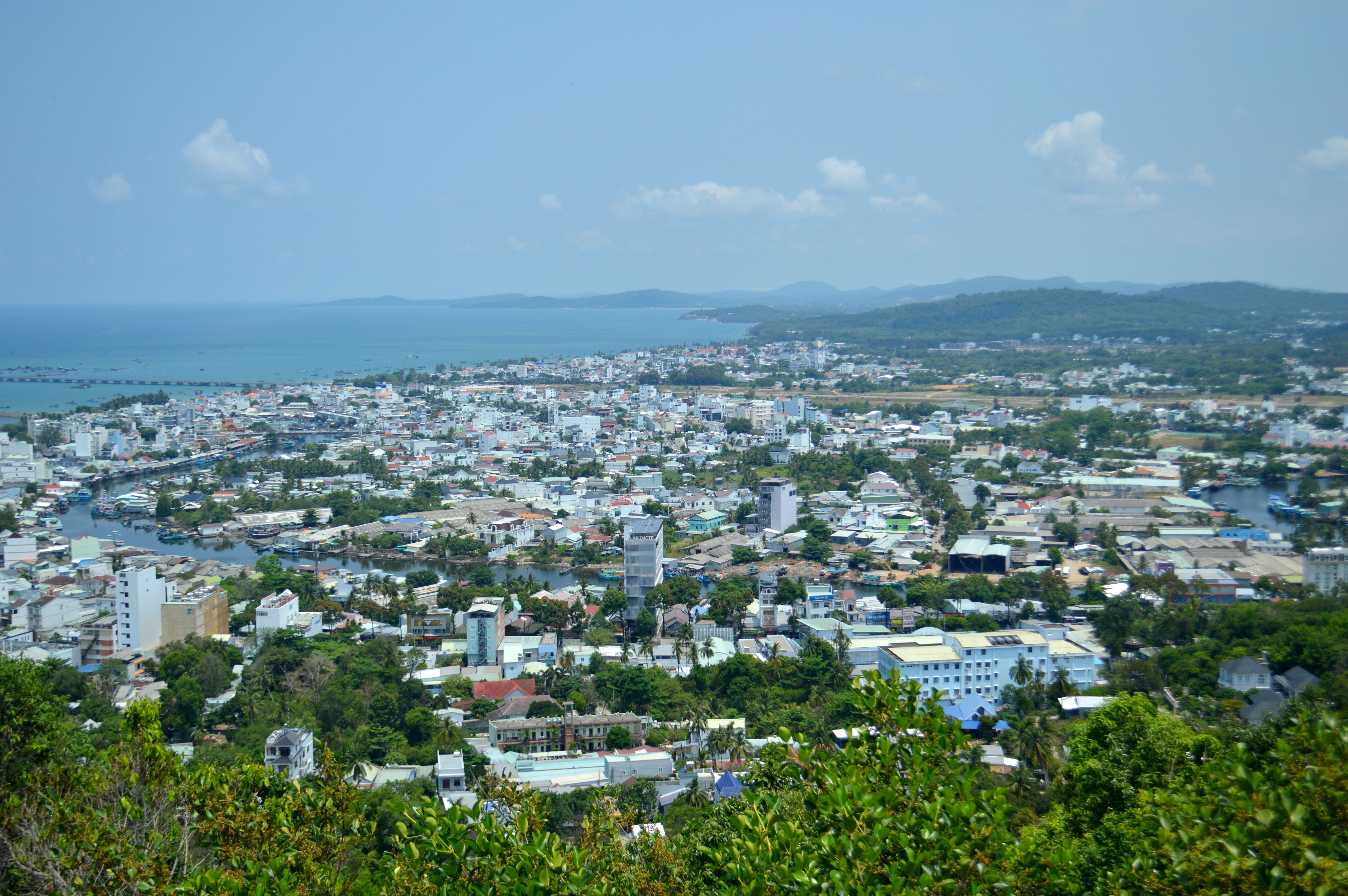 Aerial view of a vibrant coastal city with an expansive ocean backdrop on a clear summer day.