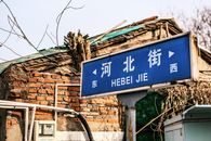 Street sign for Hebei Jie in front of rustic brick building, China.