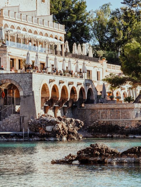 Charming coastal hotel with elegant arches overlooking the Mediterranean Sea, offering a scenic vacation spot.