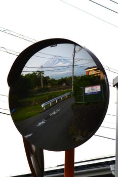 Mount Fuji is reflected in a rural Japan traffic mirror.