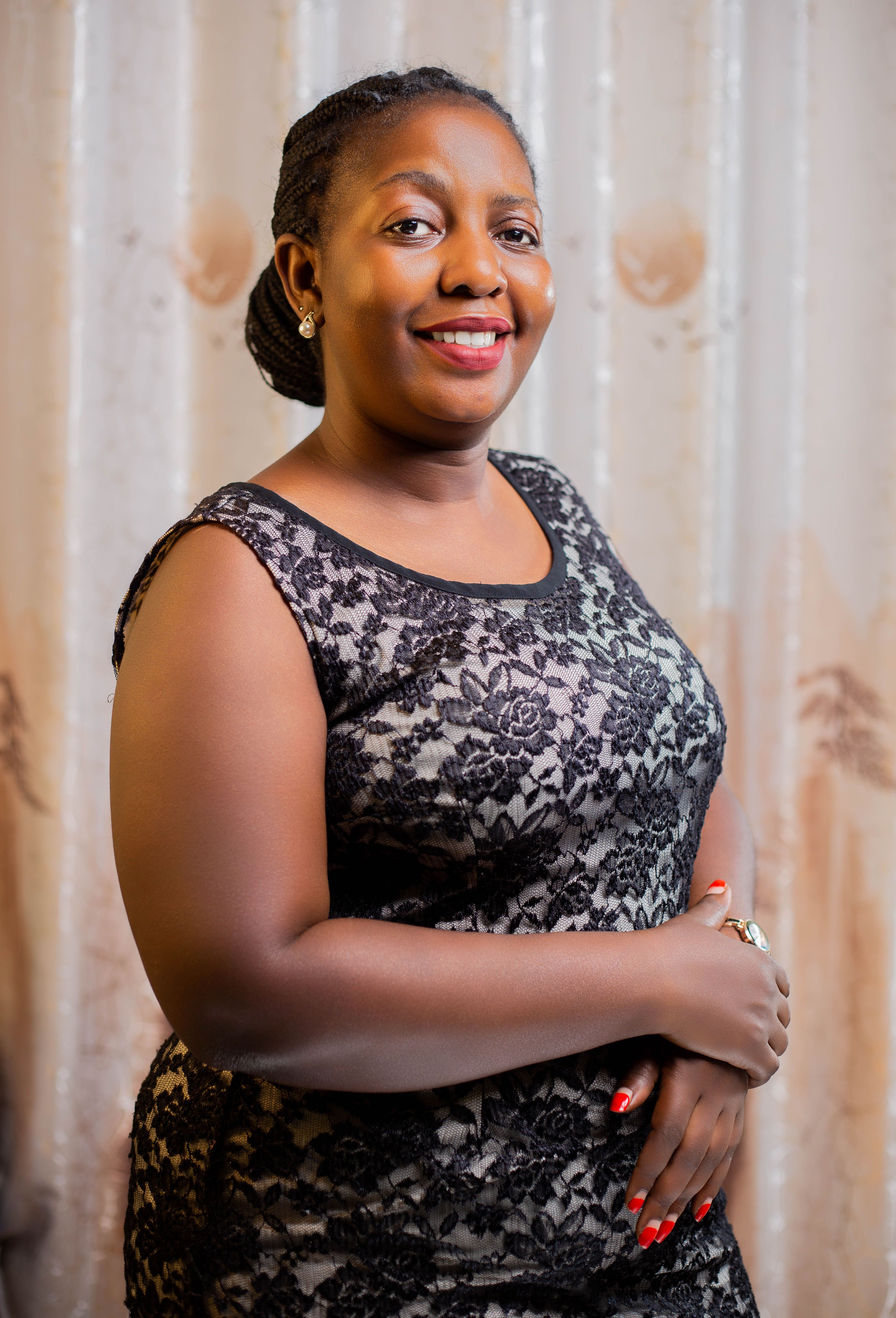 A confident woman in a stylish lace dress posing indoors with a warm smile and elegant posture.