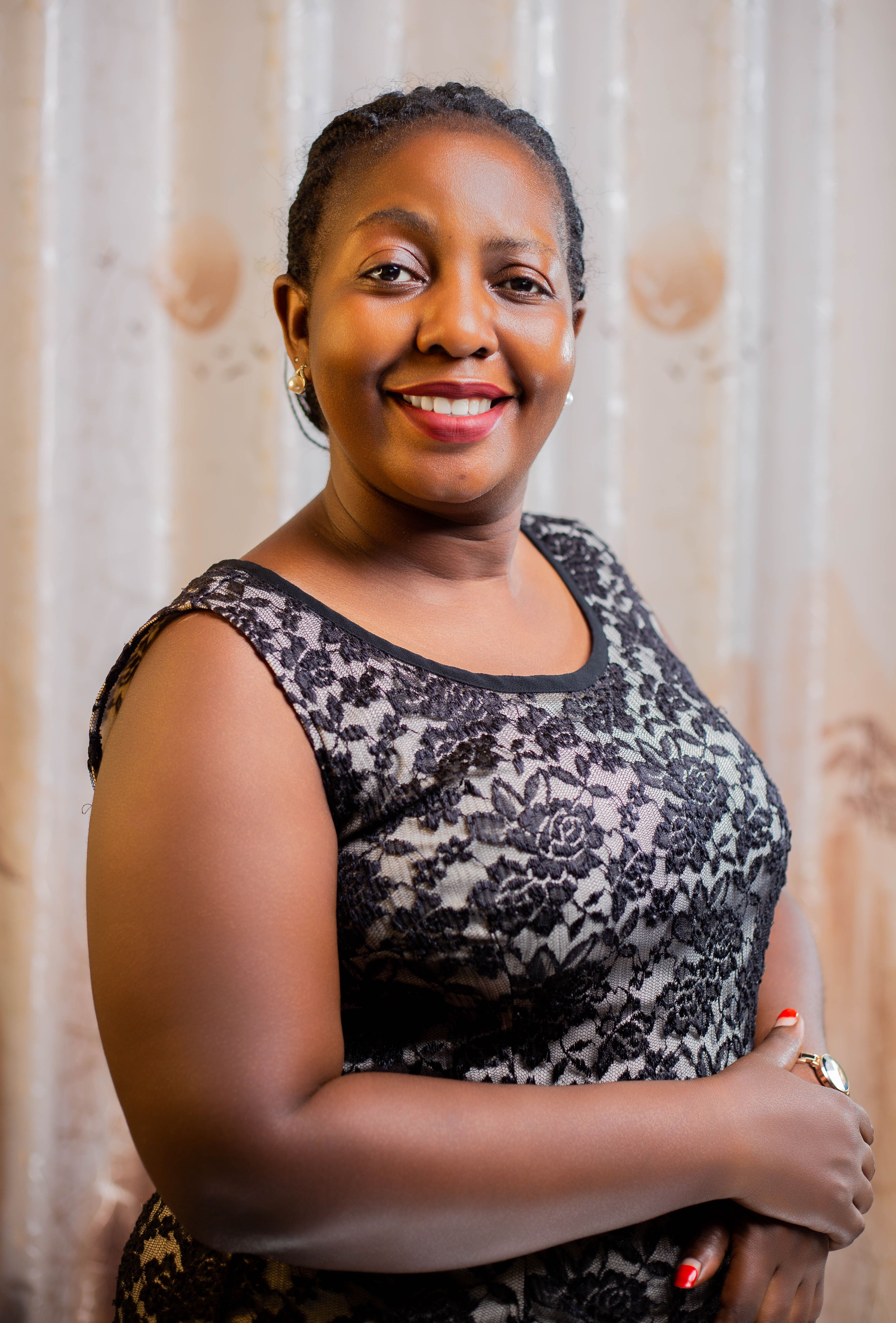 Portrait of a smiling woman wearing a lace dress, posing indoors against a patterned background.