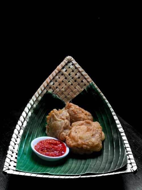 Free Delicious fried tempeh served with spicy sambal on banana leaf plate. Perfect for authentic Indonesian cuisine lovers. Stock Photo