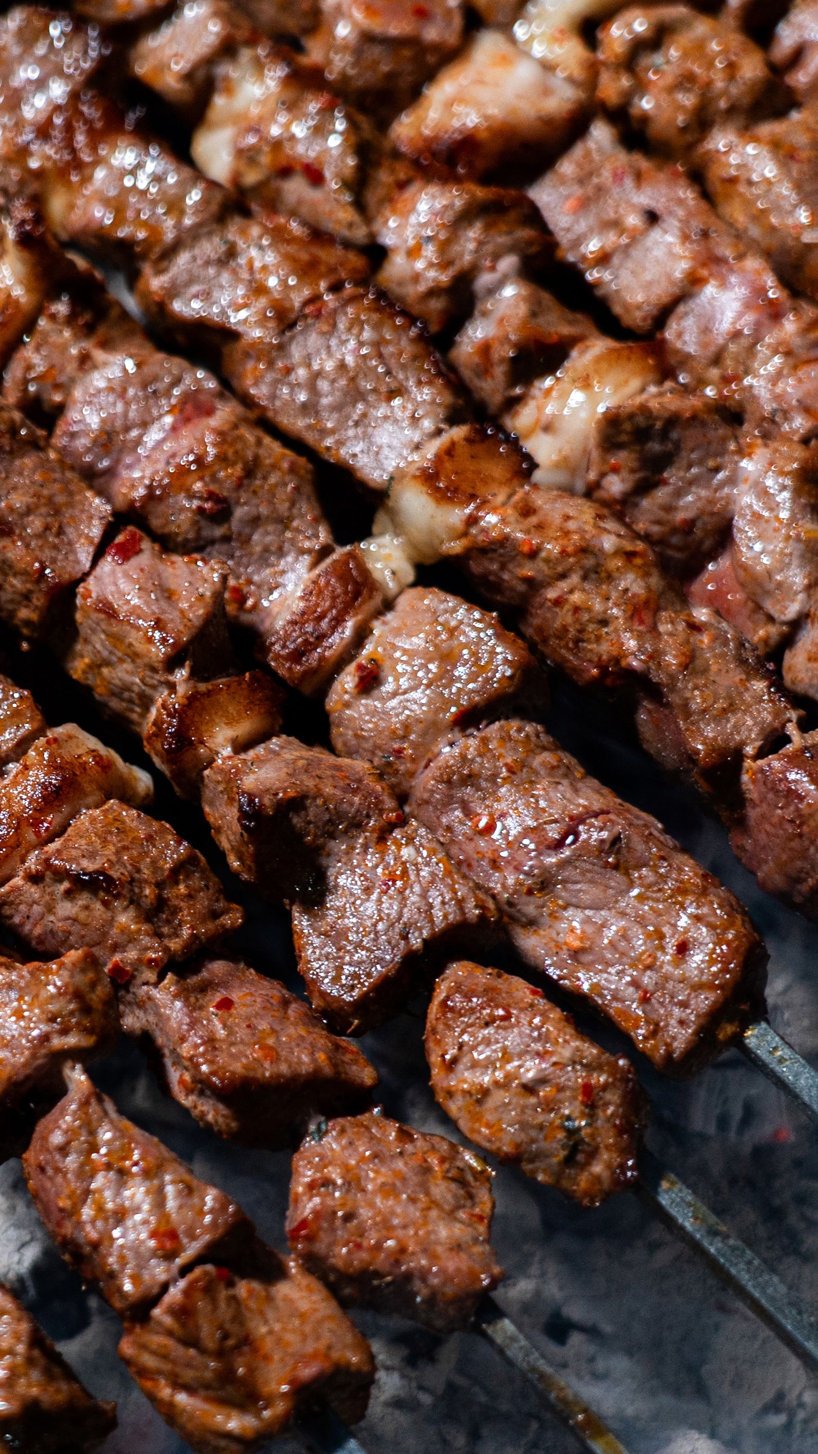 Close-up of deliciously grilled beef kebabs on skewers with a smoky background.