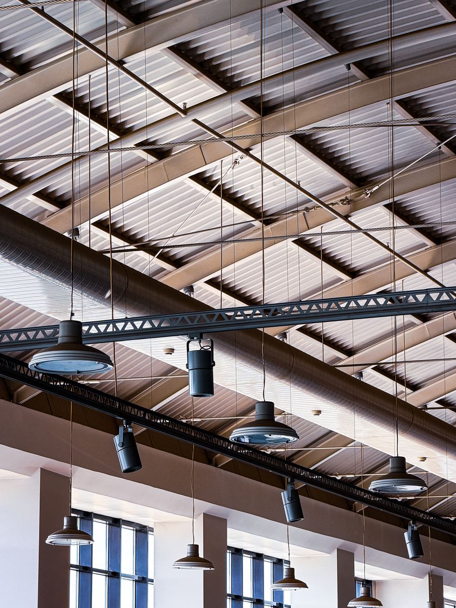 Commercial ceiling with exposed structure, suspended light fittings and services overhead