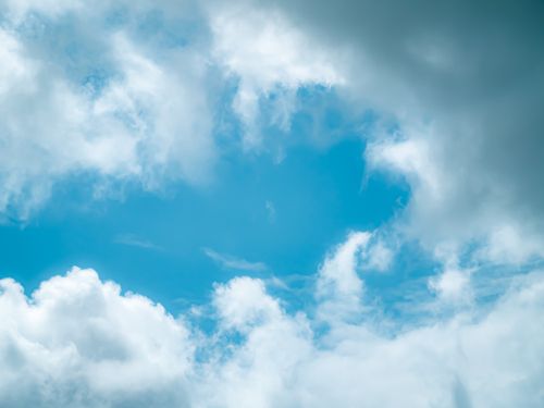 Free A peaceful blue sky adorned with fluffy white clouds on a clear day. Stock Photo