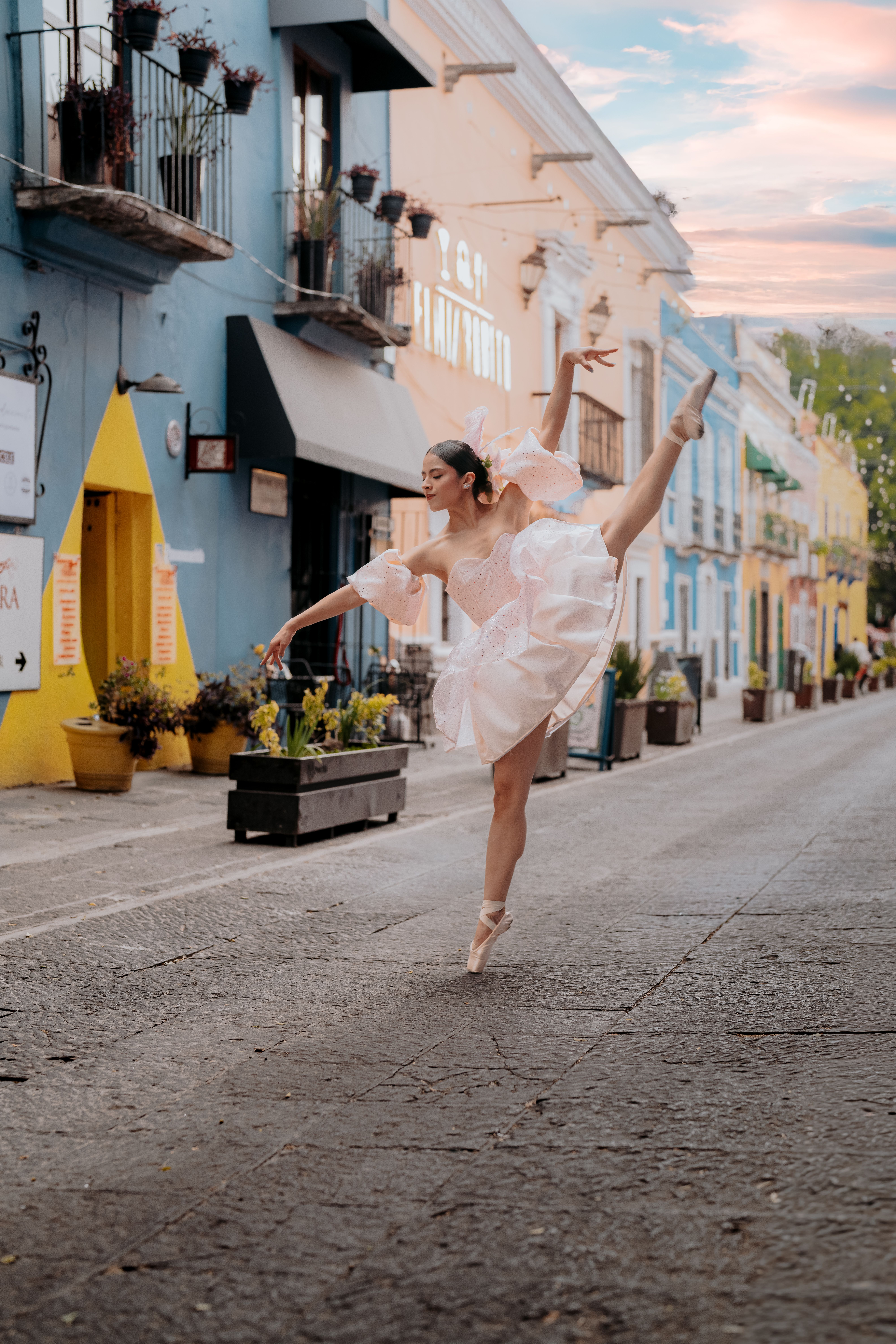 A graceful ballerina in a pink dress performs a dance on a vibrant street in Puebla, Mexico.