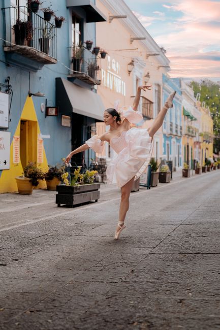 A graceful ballerina in a pink dress performs a dance on a vibrant street in Puebla, Mexico.