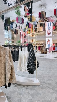 Interior view of a stylish fashion store featuring a vibrant mirror ceiling and clothing racks.