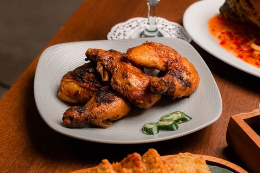 Succulent grilled chicken drumsticks served with jalapeno slices on a ceramic plate.