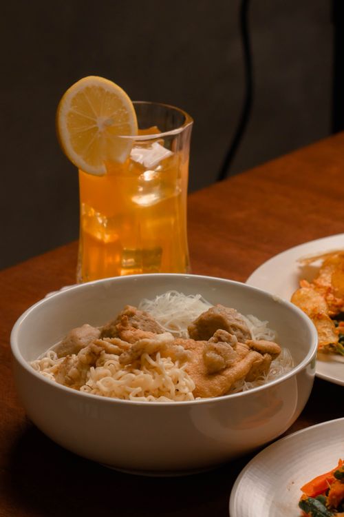 Free A tasty bowl of noodles with fried chicken and lemon iced tea, perfect for a cozy meal. Stock Photo