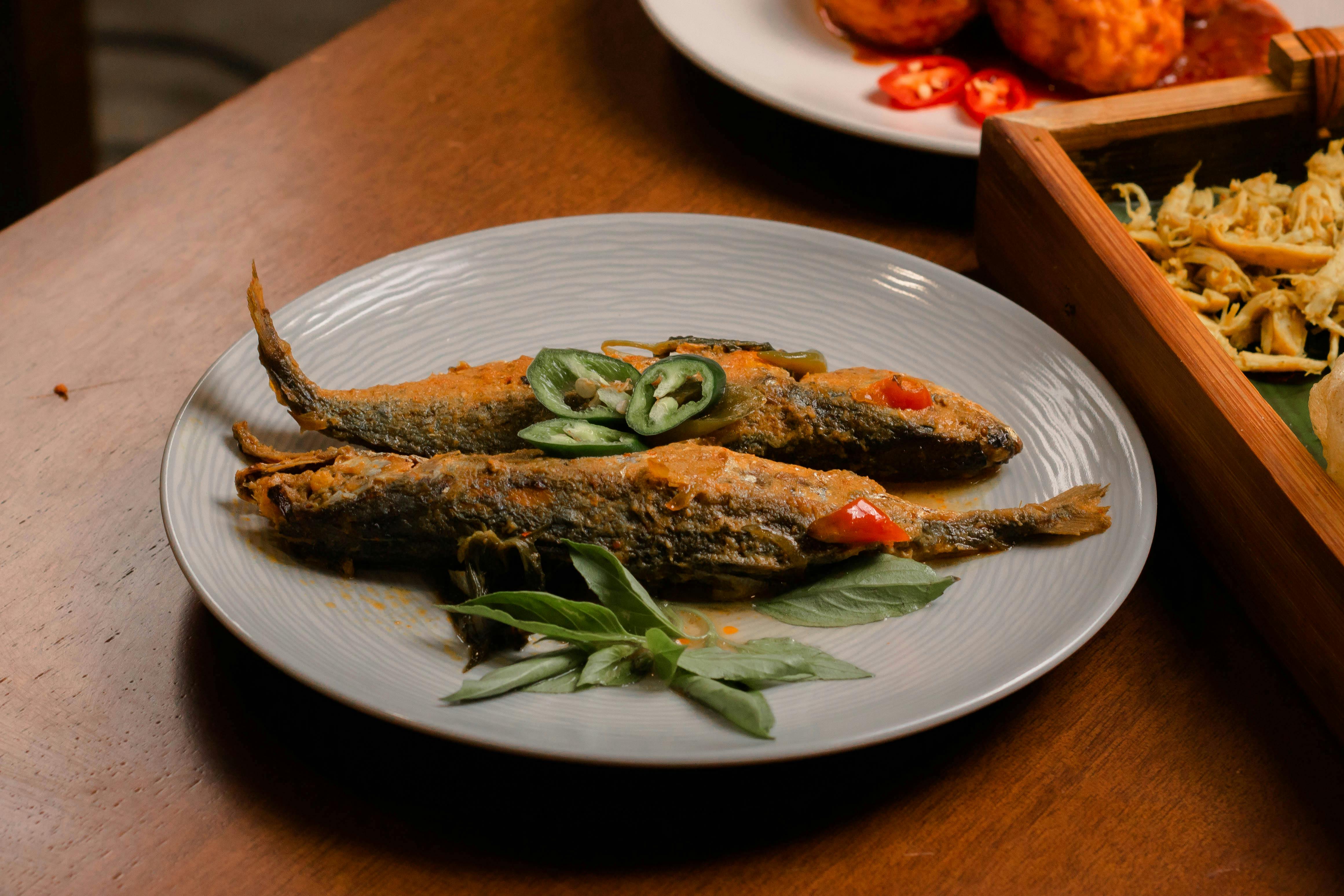 Grilled fish served on a plate with fresh herbs and chilies, perfect for culinary dishes.