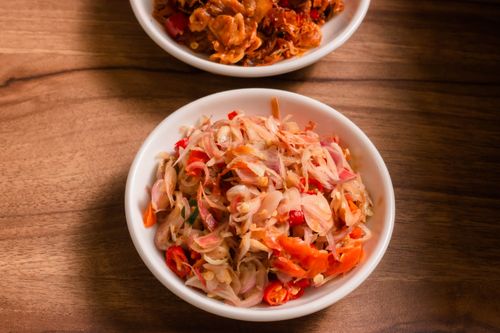 Free Close-up of an Indonesian sambal dish in a white bowl on a wooden table, spicy and vibrant. Stock Photo