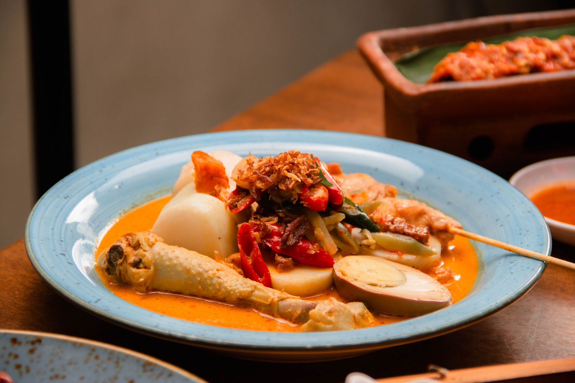 A vibrant and colorful traditional Indonesian dish featuring lontong sayur with chicken, vegetables, and eggs.