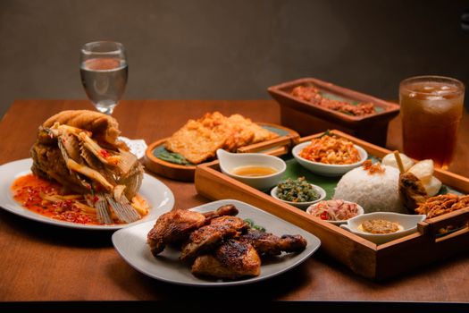 A vibrant display of traditional Indonesian dishes served on a wooden table, showcasing flavorful Asian cuisine. - Fotografer Sidoarjo