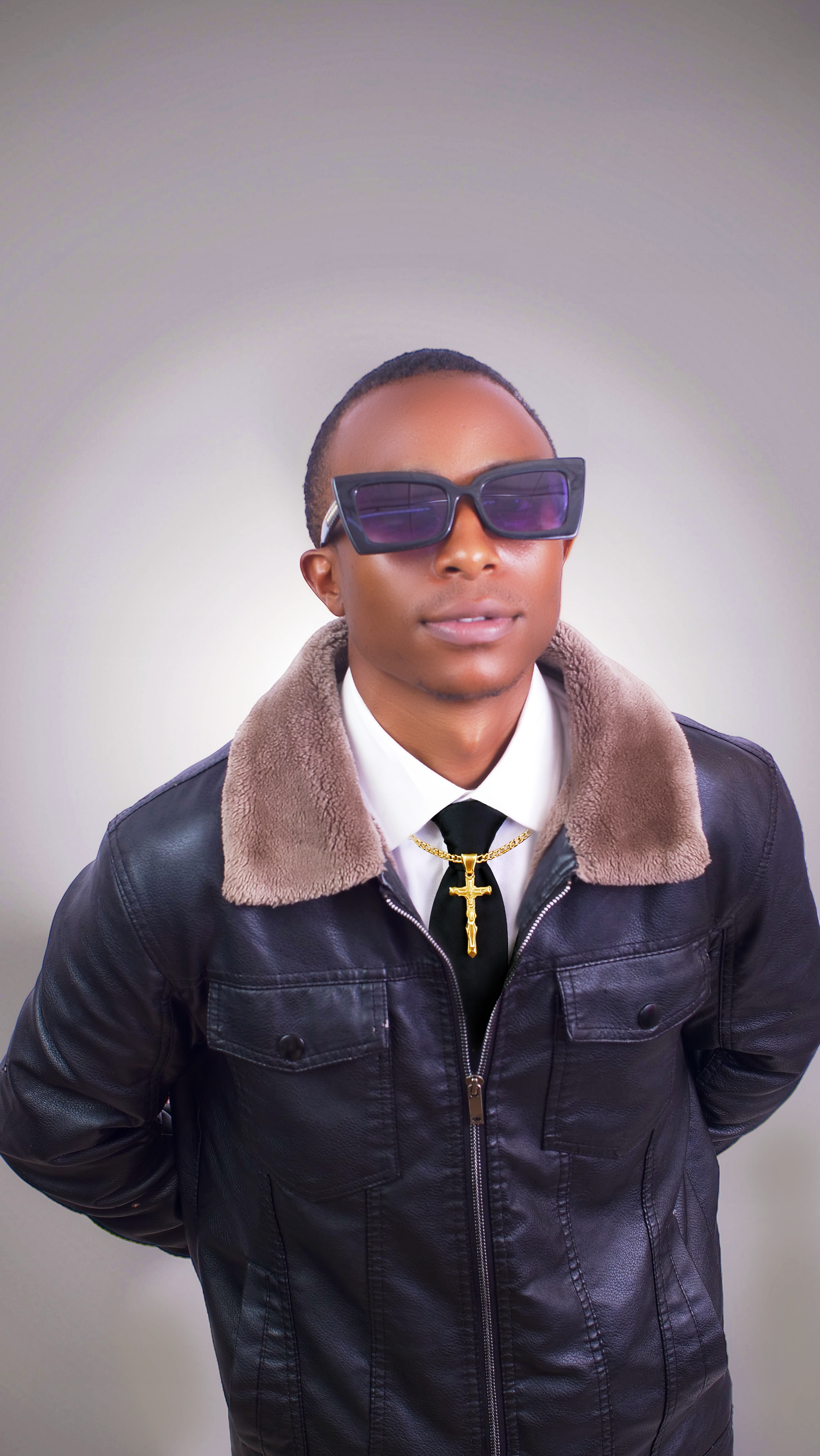 Confident young man wearing sunglasses and a black leather jacket with a fur collar.