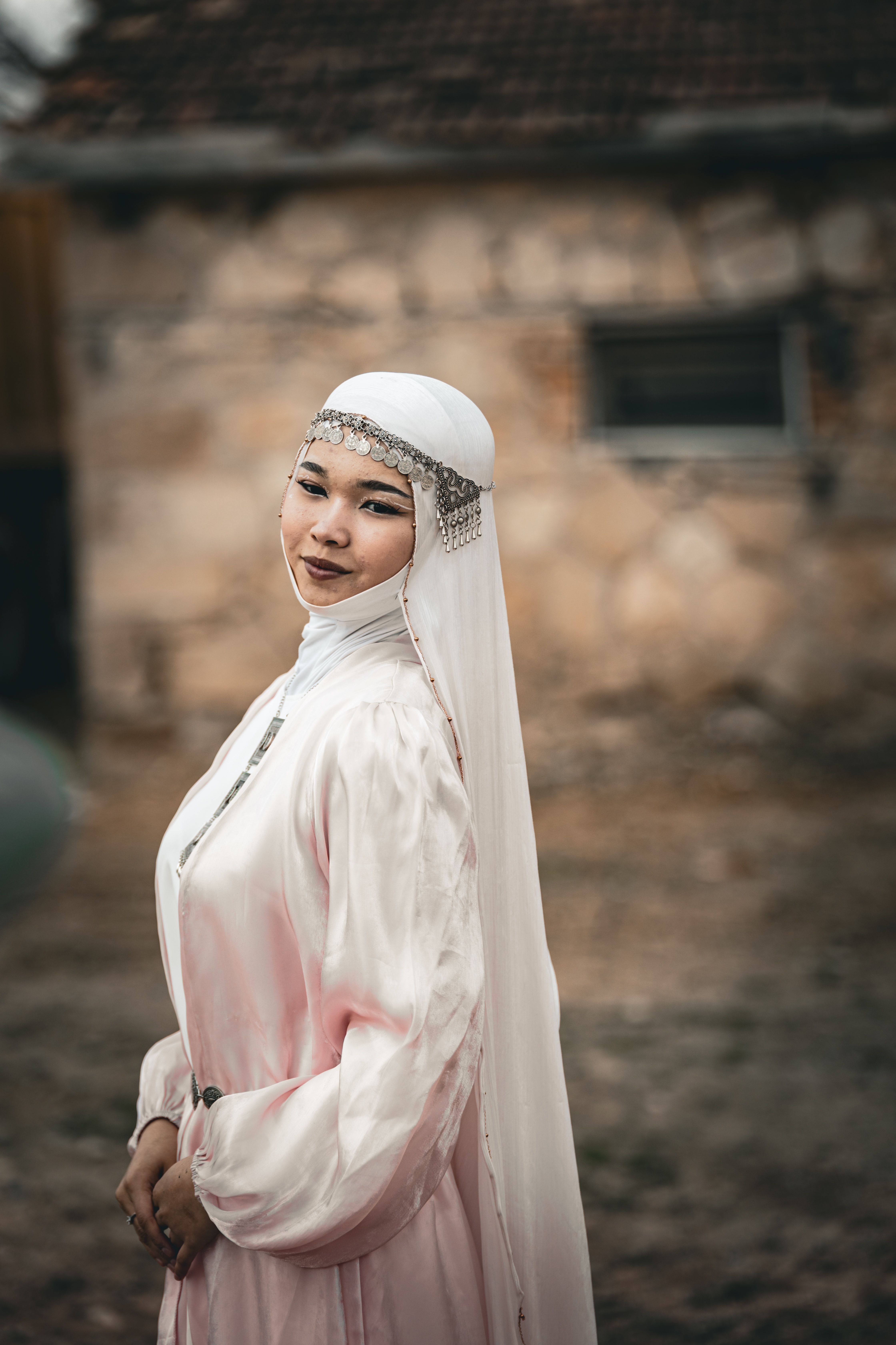 A young woman poses in traditional attire with a serene expression in an outdoor setting.
