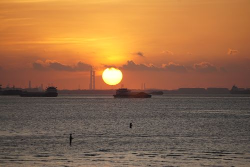 Free A breathtaking sunset over a calm ocean with silhouetted boats on the horizon. Stock Photo