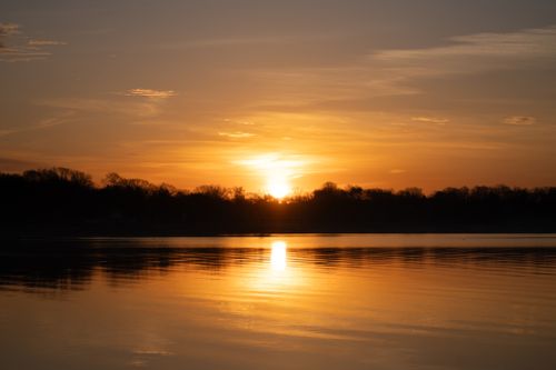 Free Serene sunset view with warm golden hues reflecting over a calm lake surface. Stock Photo