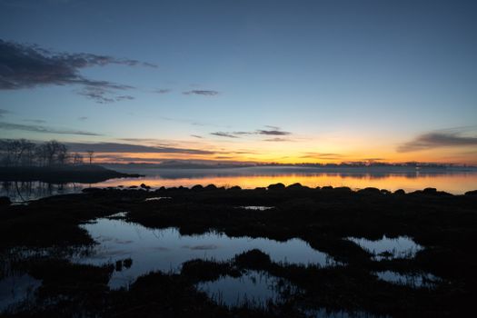 A tranquil sunrise scene featuring a calm lake and vibrant sky reflections.