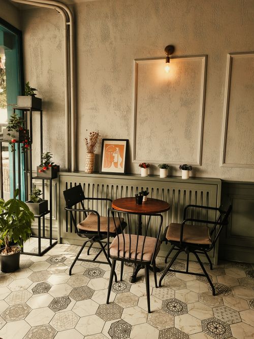 Free Warm cafe interior featuring a minimalist design, potted plants, and vintage furniture, creating an inviting atmosphere. Stock Photo