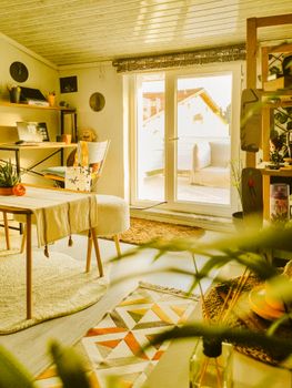 Inviting attic room with bohemian decor and warm sunlight streaming in through French doors.