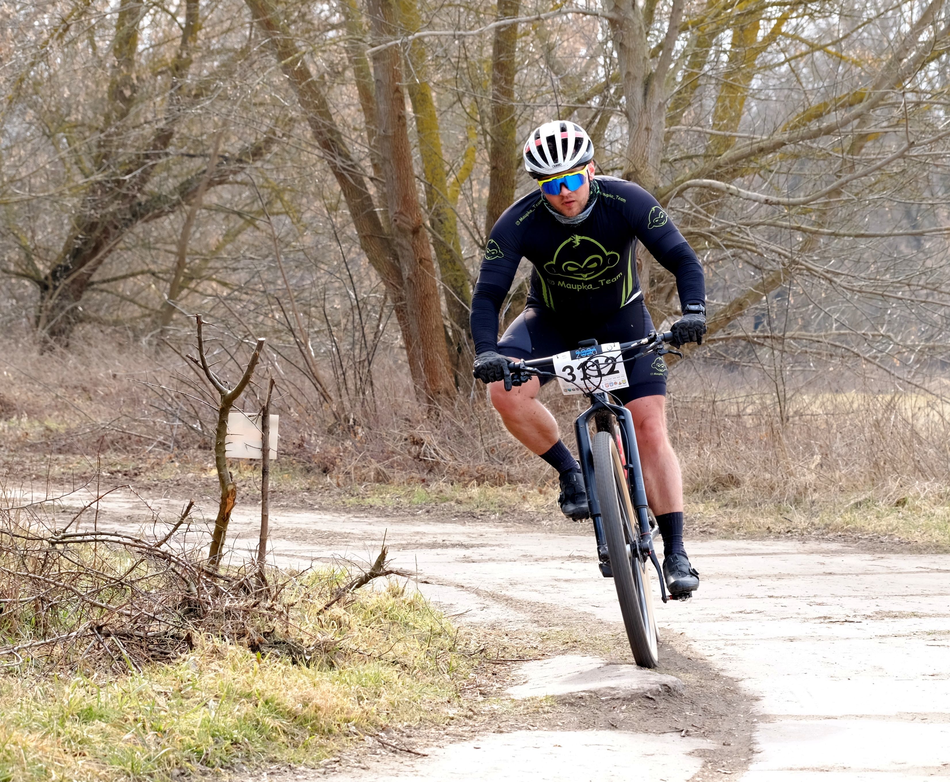 Cyclist competes in a forest trail race during early spring.