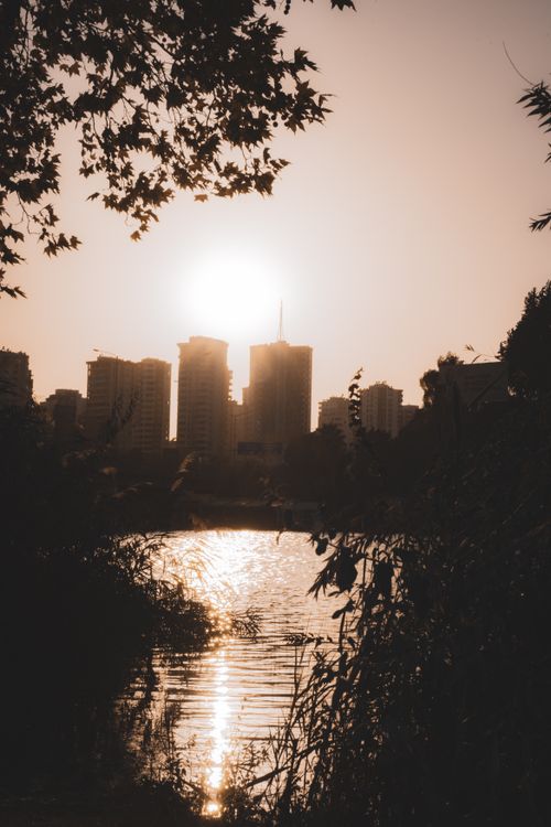 Free Captivating city skyline silhouette with sunset reflecting on tranquil water. Stock Photo