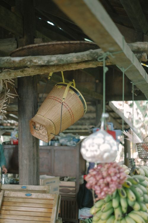 Free Rustic market setting featuring a hanging woven basket and fresh produce. Stock Photo