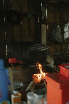 A cozy indoor fire in a rustic wooden kitchen setting with cookware around.