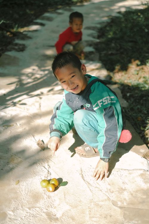 Free Two children enjoy a sunny day playing on a stone pathway outdoors. Stock Photo