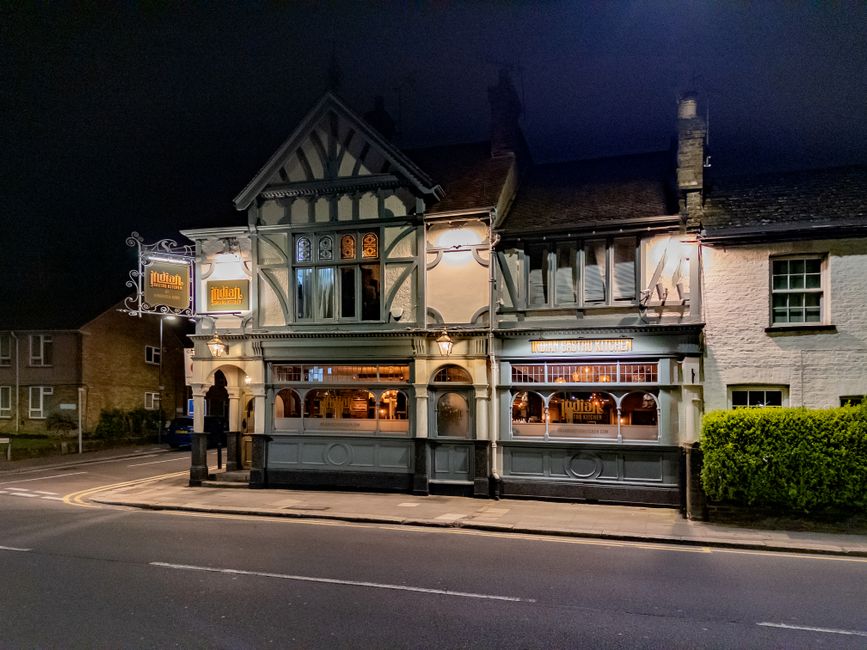 Illuminated traditional English pub in Harrow at night, showcasing classic architecture.