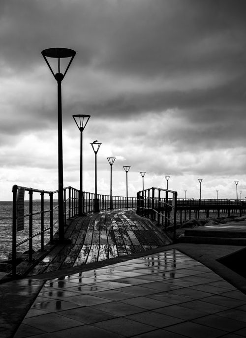 Free Dramatic seascape with a wooden pier under overcast skies, perfect for conveying solitude. Stock Photo